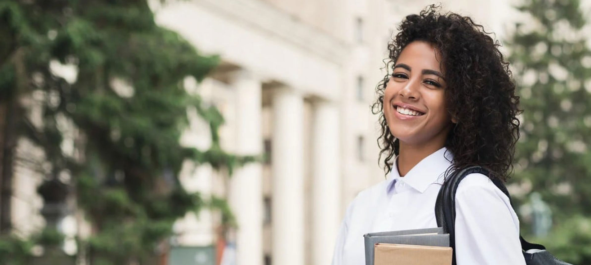 A student holding a book on campus.