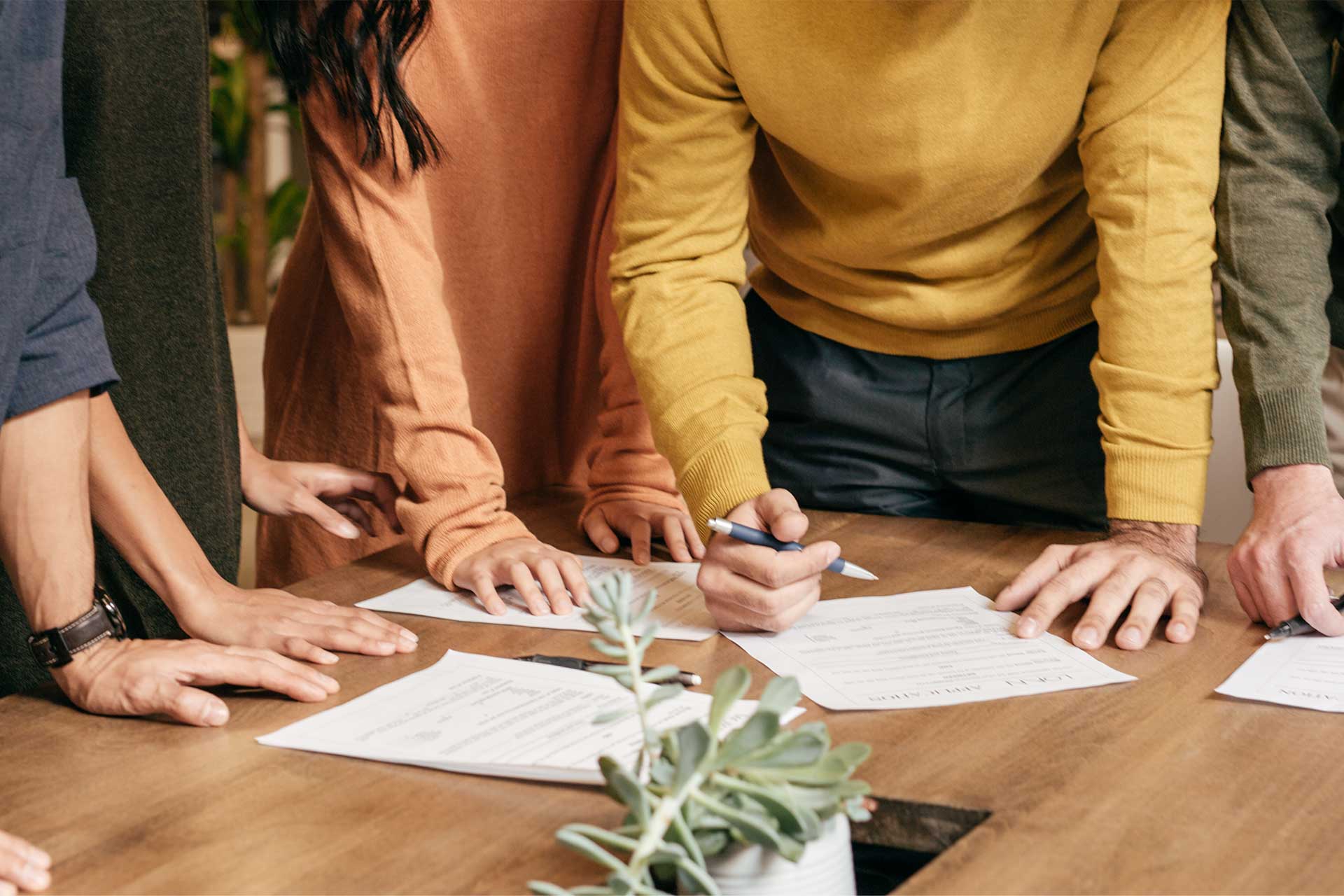 A group of people brainstorming, just their hands visible